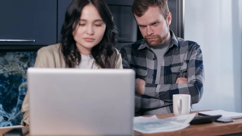 Couple intently discussing household finances and debt consolidation while using a laptop at their table
