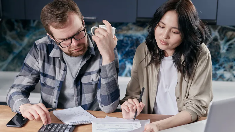 A couple reviewing household bills and mortgage budget using a calculator at their table