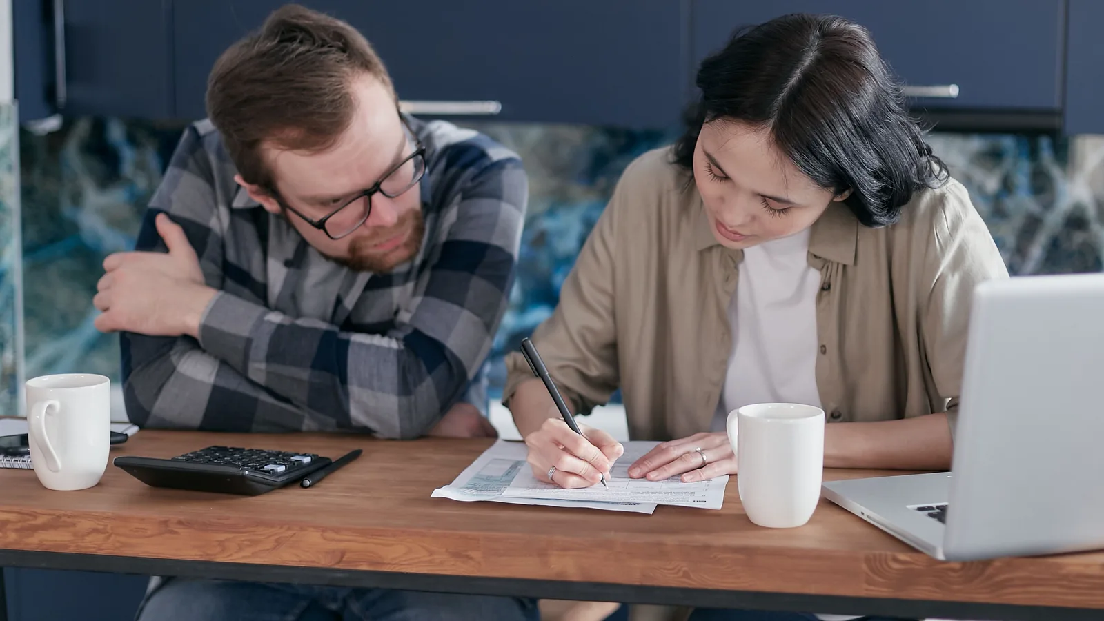 Couple reviewing bank statements and financial documents with a laptop