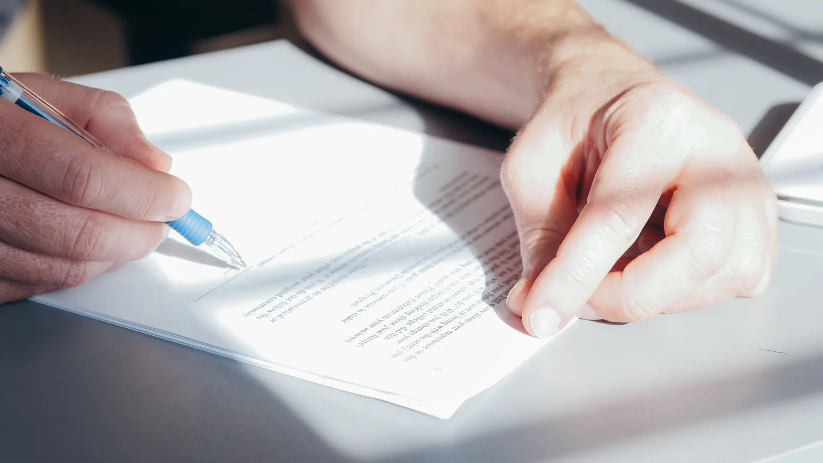 Person reviewing and signing a bank gift declaration letter with a pen