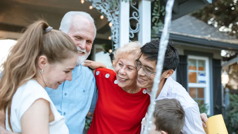 Parents and their adult children standing together outside a family home