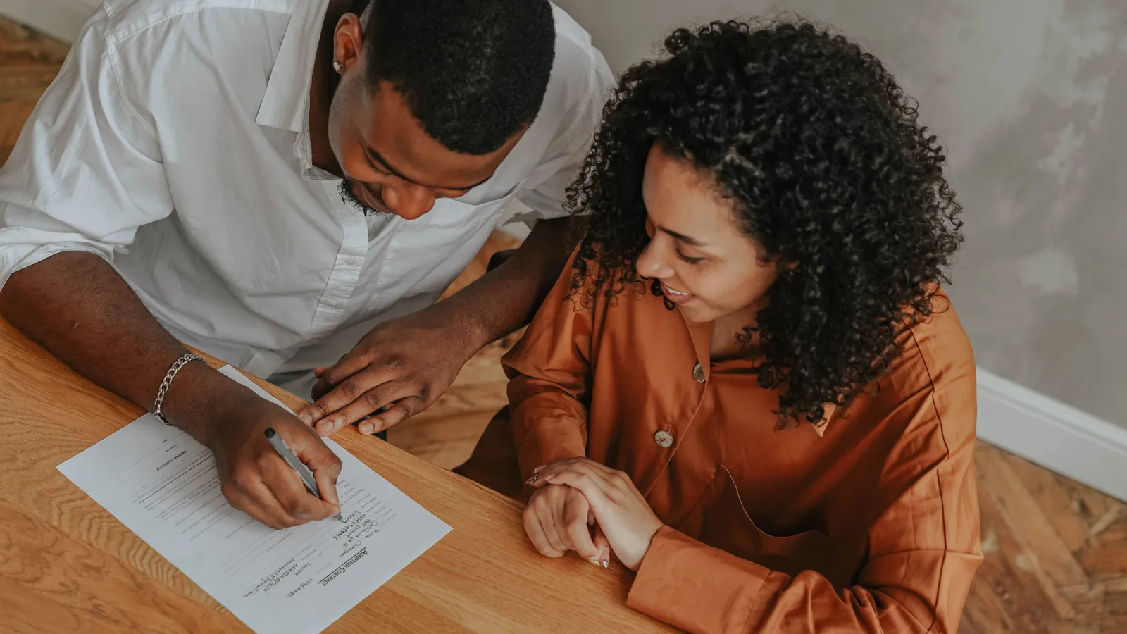 Person signing a mortgage guarantee document at a desk with a pen