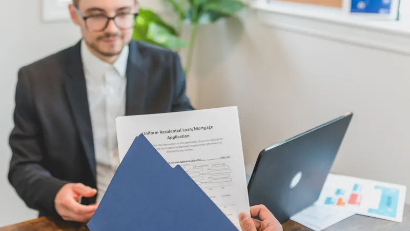 Home loan adviser handing a mortgage application document across a desk