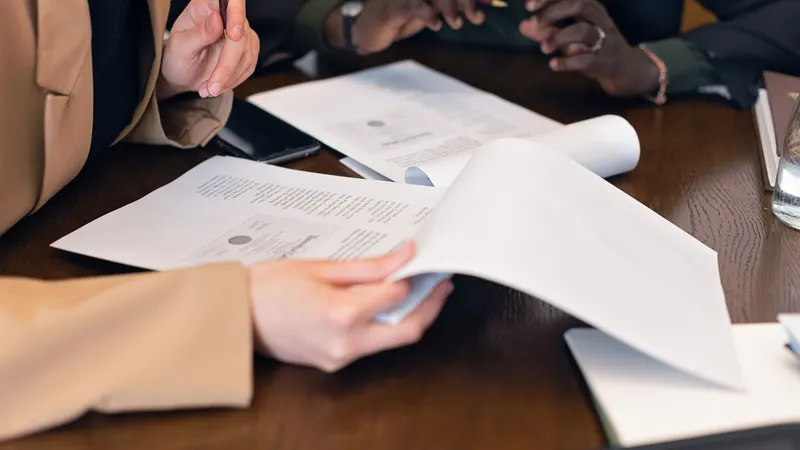 Two people closely reviewing and comparing loan documents side by side at a desk