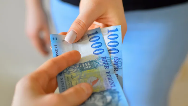 Close-up of hands exchanging New Zealand banknotes, representing a mortgage cash back payment