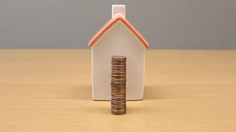 Small model house next to a stack of coins, representing a home loan deposit in NZ