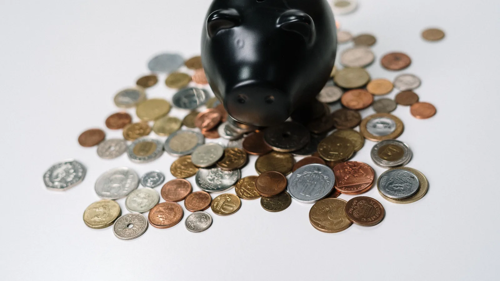 Piggy bank surrounded by saved coins, representing genuine savings toward a house deposit