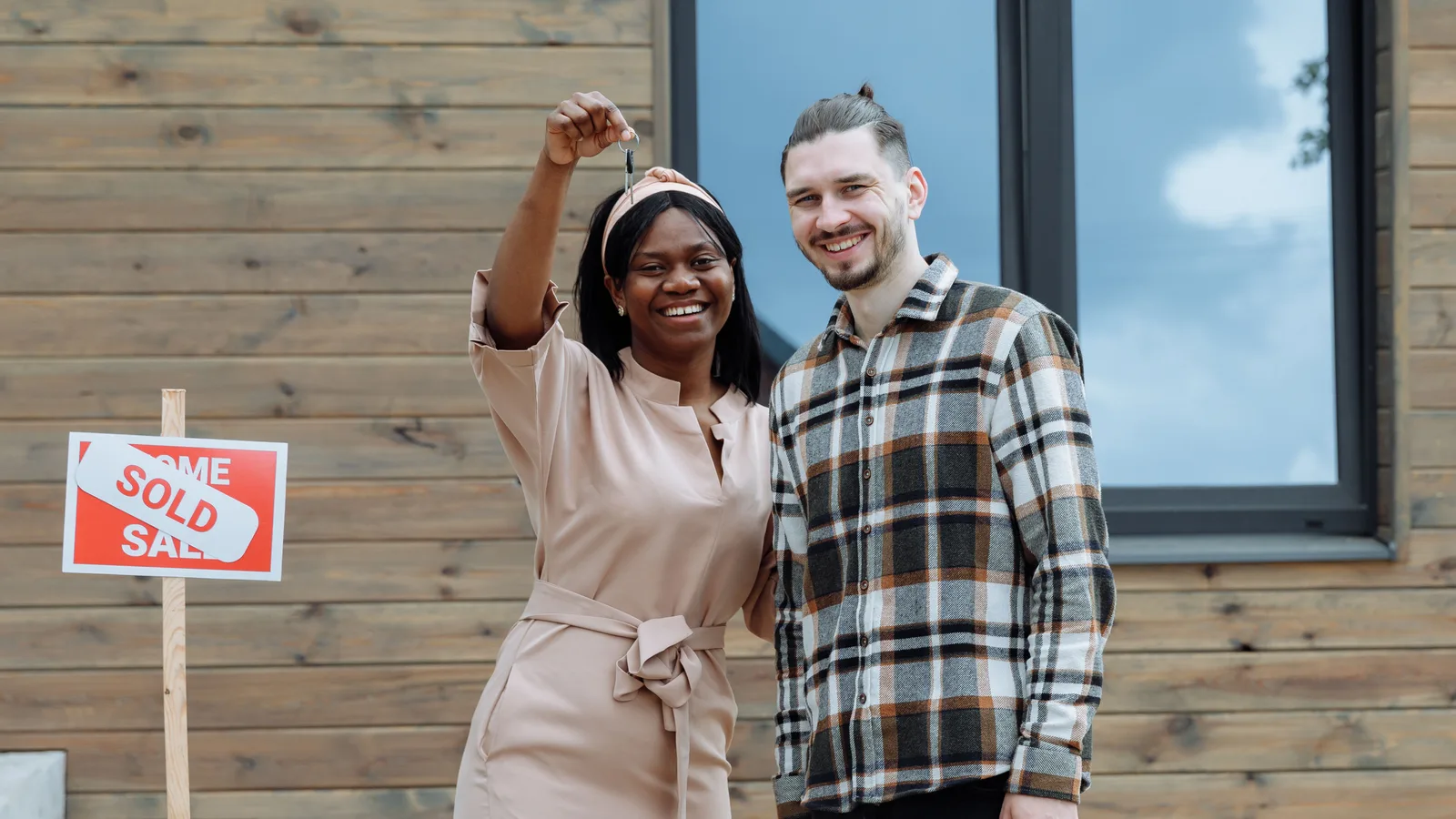 Couple holding house keys outside their newly purchased first home