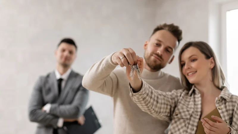 Young couple holding house keys in front of their new home