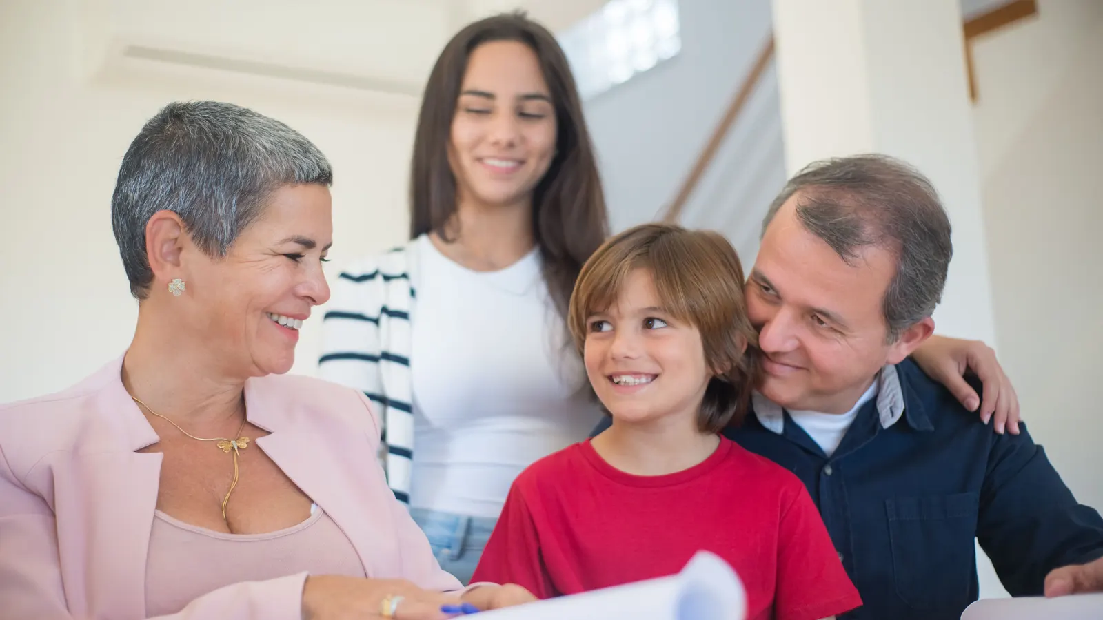 Three generations of a family smiling together while reviewing paperwork at home