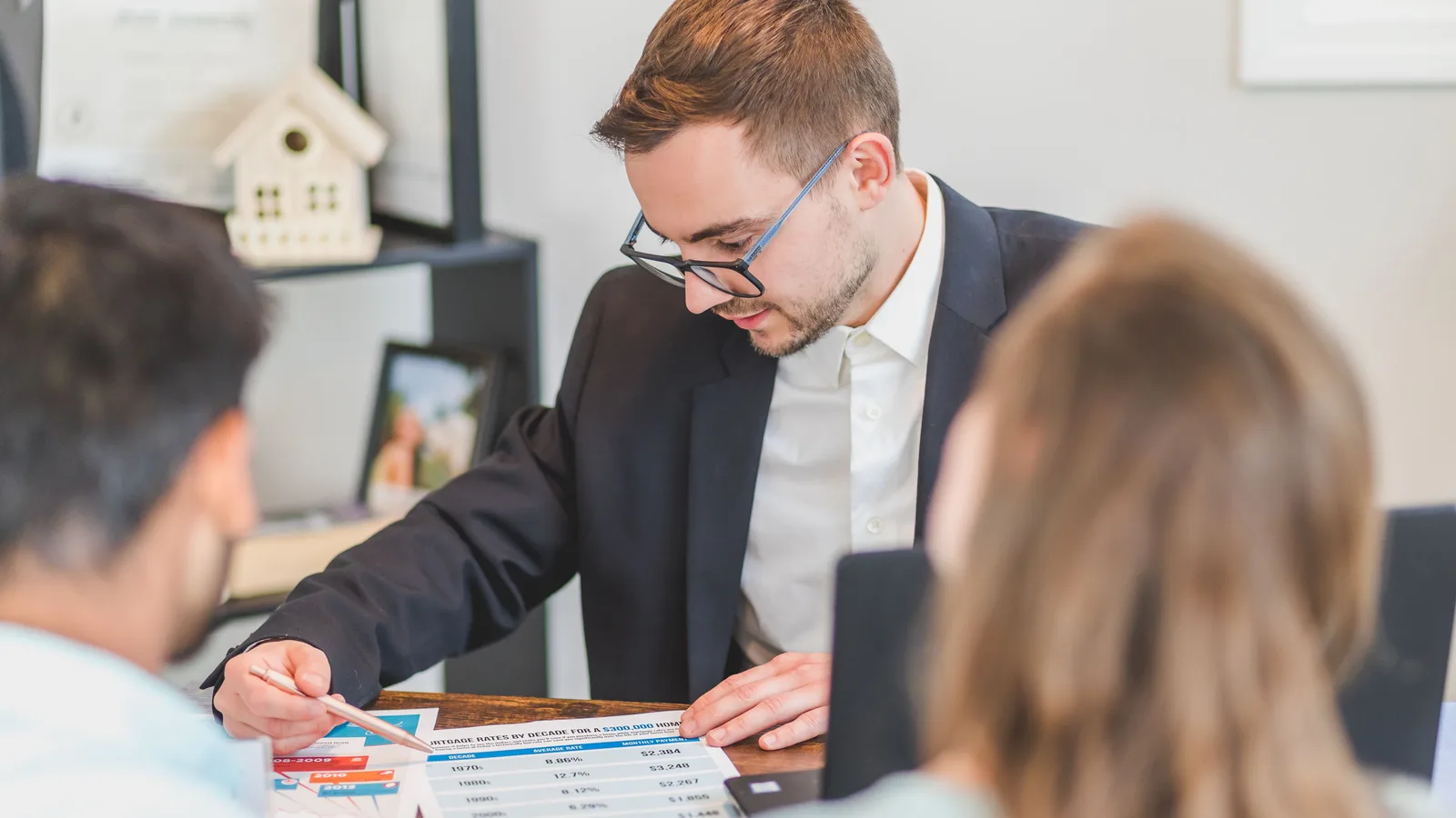Home loan adviser explaining mortgage strategy to clients across an office desk