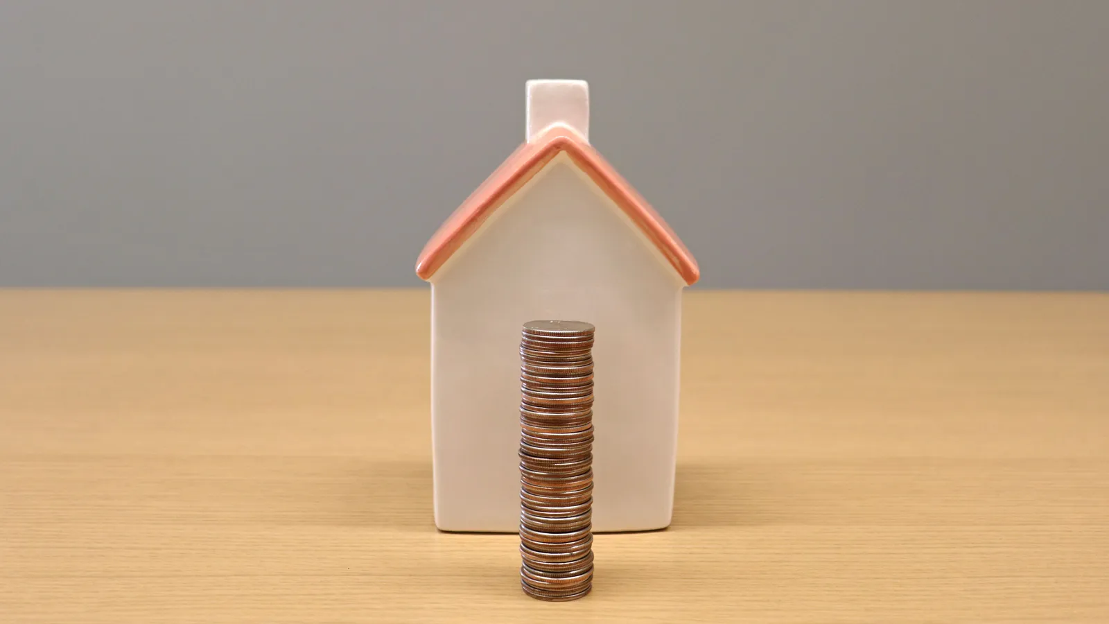 Stack of coins beside a small model house, representing extra mortgage repayments