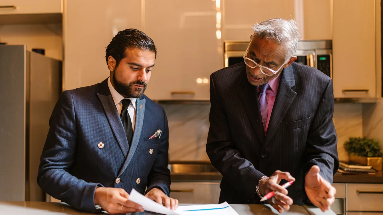 Adviser reviewing mortgage structure documents with a client in a kitchen